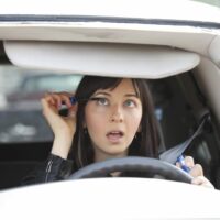 Woman Putting On Eyeliner While Driving Stock Photo