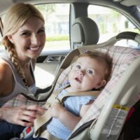 Woman Putting Her Baby In A Car Seat Stock Photo