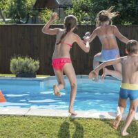Children jumping into a swimming pool stock photo