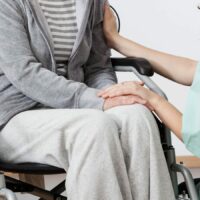 Consoling Woman In Wheelchair Stock Photo